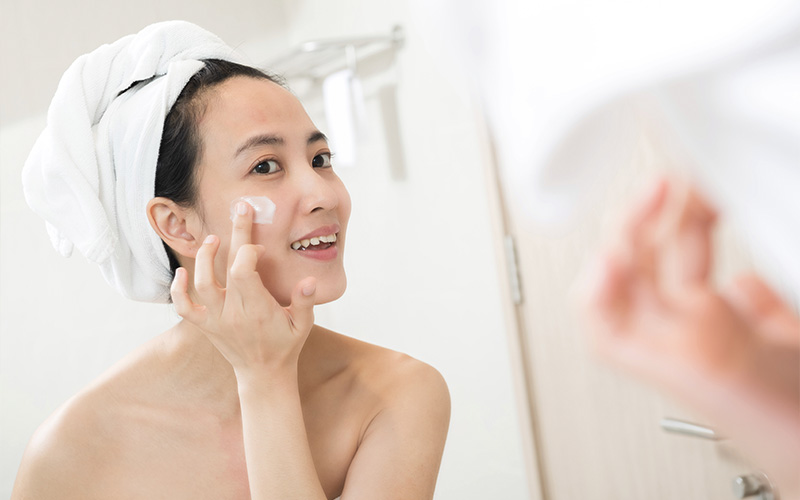 Asian beauty woman apply lotion on her face in the bathroom 