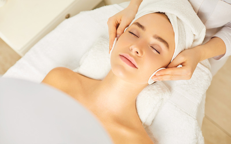 Beautician applying facial treatment for female customer