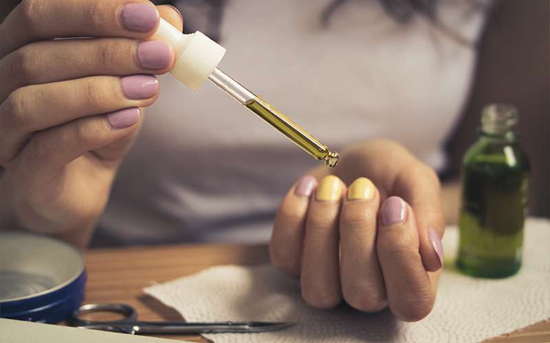 Female hand holding a pipette with oil