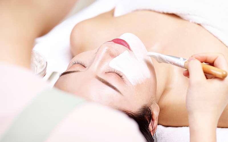 Beautician Brushing Herbal Cream On Face Of Customer