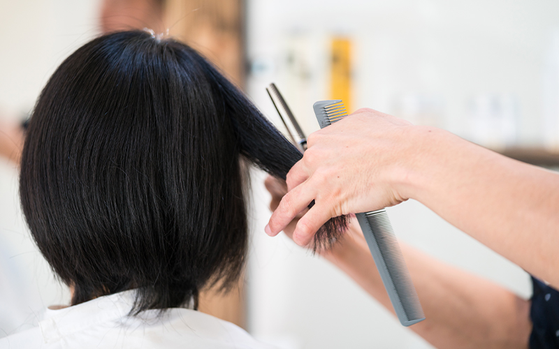 A woman getting her hair trimmed by a hairdresser