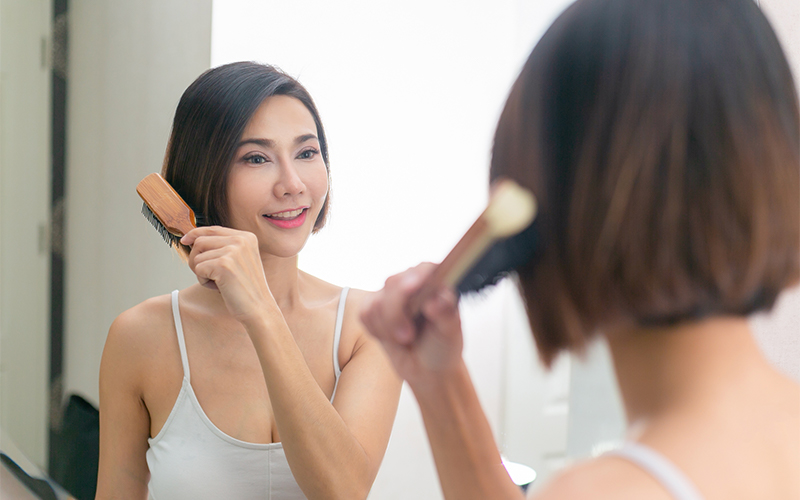 Asian woman having fun combing her beautiful hair