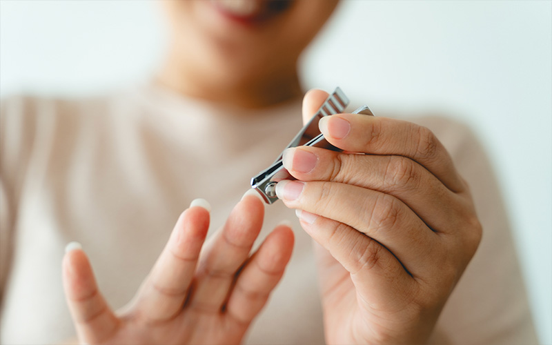A woman is holding a pair of nail clippers